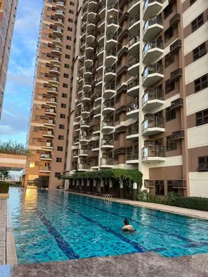 a person in a swimming pool in front of a building at Bayview near CCP, PICC, Airport, MOA, Okada at Radiance in Manila