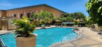 a swimming pool with trees in front of a building at The Venice Luxury Residences Condominium 28B Bellini, McKinley Hill, Taguig City, Philippines in Manila