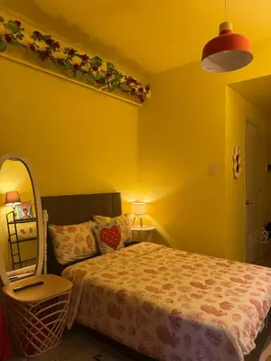 a yellow bedroom with a bed and a mirror at The Cozy Palette Manila in Manila