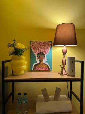 a table with a lamp and a vase with flowers on it at The Cozy Palette Manila in Manila