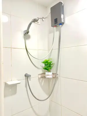 a shower with a hose and a plant in a bathroom at Amari Staycation - Alabang in Manila