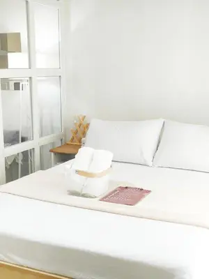 a white bed with two rolls of towels on it at The Crash Pad Soho Central in Manila