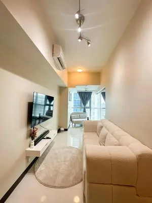 a living room with a couch and a flat screen tv at Uptown District Stay in Manila