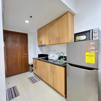 a kitchen with wooden cabinets and a stainless steel refrigerator at OASIS by JK Suites in Manila