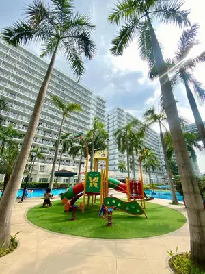 a playground in front of a large building with palm trees at OASIS by JK Suites in Manila