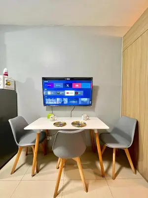 a table with chairs and a computer monitor on a wall at Shore 8109 onebedroomwbalcony in Manila