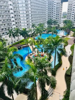 an aerial view of a pool with palm trees and buildings at Zeth's Place at Shell Residences Near MOA and NAIA in Manila