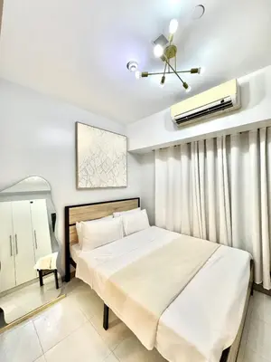 a bedroom with a white bed and a ceiling fan at Arcadia Suites Manila at Acqua in Manila