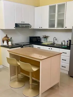 a kitchen with white cabinets and a wooden counter top at Stad en Thuis - Mckinley Hill, Taguig in Manila
