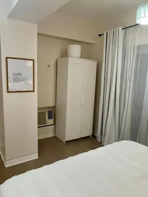 a bedroom with a white bed and a cabinet at Stad en Thuis - Mckinley Hill, Taguig in Manila