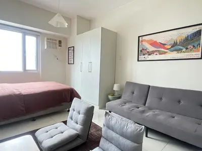 a bedroom with a bed and a couch and a chair at Cozy Nook l Accessible LRT QC l Wifi & Netflix in Manila