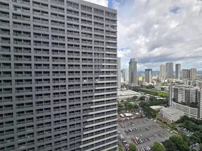 a tall white building with a city in the background at 1BR Condotel with Balcony at FAME Residences #FM62-1 in Manila