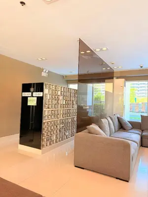 a living room with a couch and a glass wall at Sea Residences Manila Condotel by Paul in Manila