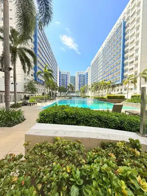 a pool in the middle of a resort with palm trees and buildings at Sea Residences Manila Condotel by Paul in Manila