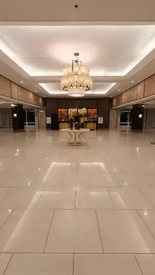 a large lobby with a large white floor and a chandelier at Shell Residences MOA - JOSH in Manila