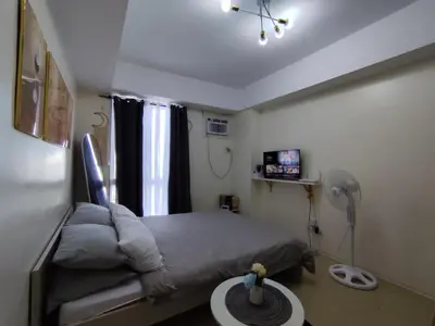 a bedroom with a bed and a table with a fan at Pet Friendly Staycation at Pasig City in Manila