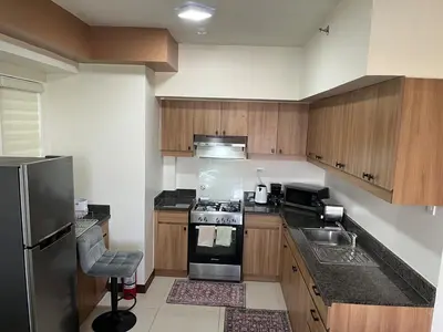 a kitchen with wooden cabinets and a stainless steel appliance at 86 sqm, 3BR condo, Free Prking, WiFi, ntflx in Manila