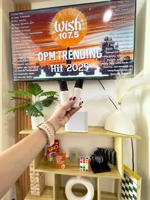 a person holding two wii remotes in front of a tv at Positano 933 in Manila