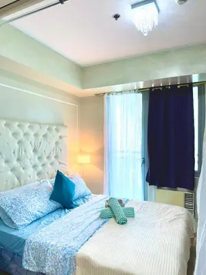 a bedroom with a large bed with blue pillows at Positano 909 in Manila