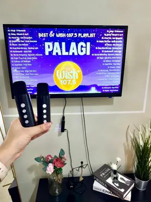 a person holding two microphones in front of a tv at Positano 909 in Manila