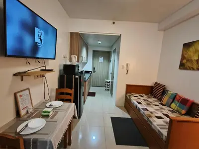 a living room with a couch and a tv on the wall at Shore Residences - Cozy 1BR Apartment near MOA in Manila