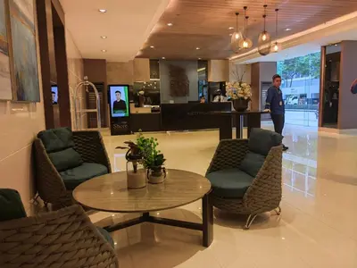 a man standing in a lobby with a table and chairs at Shore Residences - Cozy 1BR Apartment near MOA in Manila