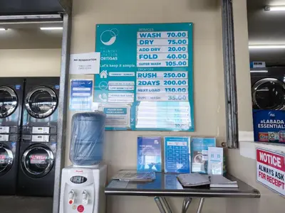 a laundry room with washing machines and a sign at Urban Oasis for 7 with 200 mbps & Netflix in Manila