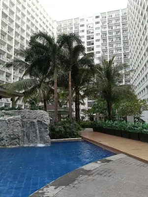 a large swimming pool with palm trees and buildings at Shore moa view in Manila
