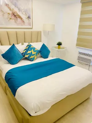 a bedroom with a large bed with blue pillows at SM Bicutan Condo by Santorini in Manila