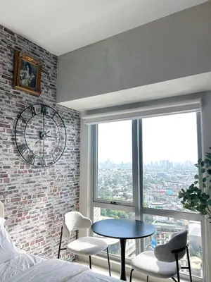 a bedroom with a clock and a table and chairs at Trescape Studio in Manila