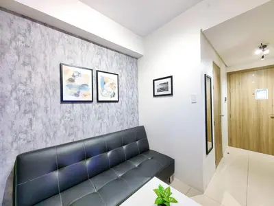 a waiting room with a black leather couch in a building at 1BR Condotel with Balcony at FAME Residences #FM03-1 in Manila