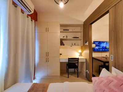 a bedroom with a bed and a desk with a table at 1BR Condotel with Balcony at FAME Residences #FM04-1 in Manila