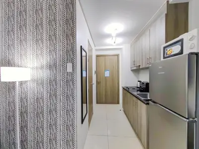 a small kitchen with a refrigerator and a hallway at 1BR Condotel with Balcony at FAME Residences #FM07-1 in Manila