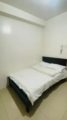 a white bed in a room with a cross on the wall at Shore Residences Tower D in Manila