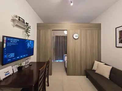 a living room with a table and a clock on a wall at 1BR Condotel with Balcony at FAME Residences #FM13-1 in Manila