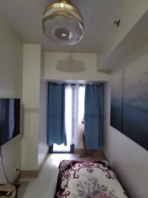 a bedroom with a bed and a window with blue curtains at Mall of Asia condotel shore 3 residence 3 in Manila