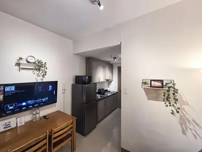 a living room with a television and a kitchen at 1BR Condotel with Balcony at FAME Residences #FM22-1 in Manila