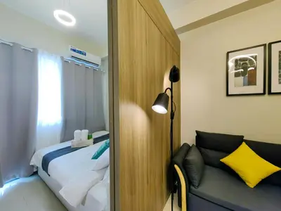 a bedroom with a bed and a lamp and a couch at 1BR Condotel with Balcony at FAME Residences #FM24-1 in Manila