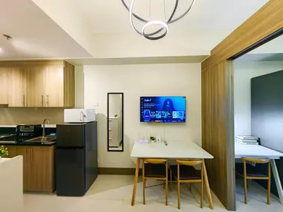 a kitchen with a white table and a black refrigerator at 1BR Condotel with Balcony at FAME Residences #FM24-1 in Manila