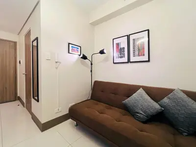 a living room with a brown couch and a lamp at 1BR Condotel with Balcony at FAME Residences #FM27-1 in Manila