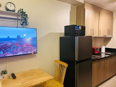 a kitchen with a refrigerator and a tv on the wall at 1BR Condotel with Balcony at FAME Residences #FM27-1 in Manila