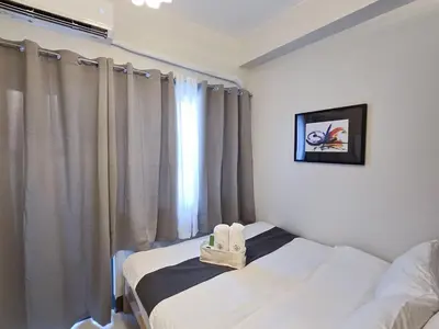 a bedroom with a bed with two white shoes on it at 1BR Condotel with Balcony at FAME Residences #FM30-1 in Manila