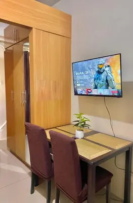 a dining room table with a tv on the wall at Fika Staycation in Manila