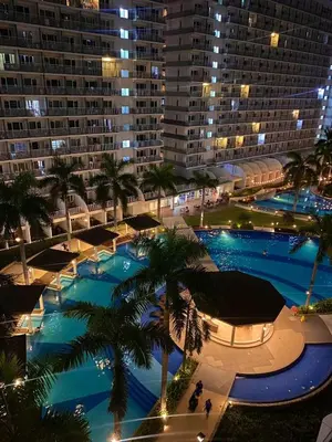 a large pool with palm trees in front of a large building at Fika Staycation in Manila