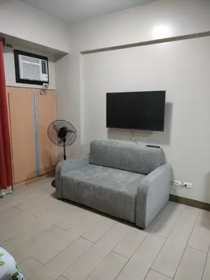 a living room with a couch and a flat screen tv at Rooms Across NAIA Terminal 3 Pasay in Manila