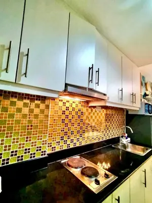 a kitchen with white cabinets and a stove top at Comfystay at Sea Residences in Manila