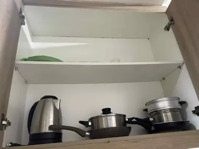 a kitchen with two pots and pans on a shelf at Walking Distance to Mall of Asia - Spacious Condo with Hot Shower and Balcony in Manila
