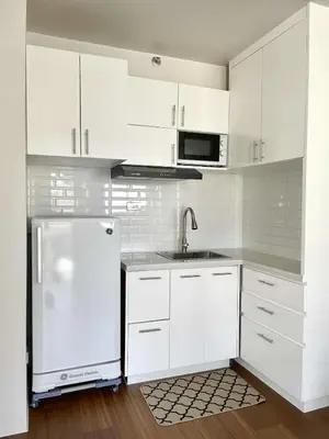 a white kitchen with a refrigerator and a sink at Warm Modern Condo Apartment with Pool & Balcony - East Residences Ortigas Pasig City in Manila