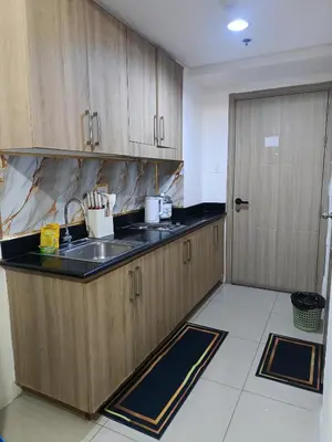 a kitchen with wooden cabinets and a sink and a door at Staycation Zone in Manila