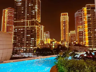 a city skyline at night with a large swimming pool at The Hotel Residences at Acqua Tower in Manila